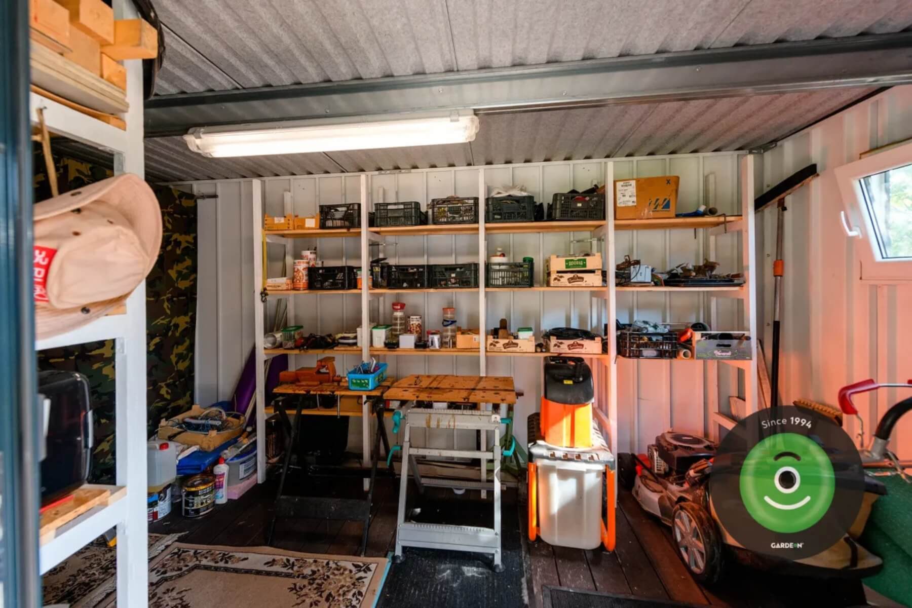 Uprataný interiér záhradného domčeka s regálmi.