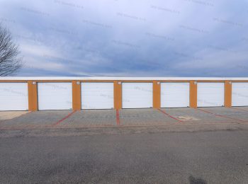 Montované radové garáže v kukuricovej omietke s bielymi garážovými bránami Hormann
