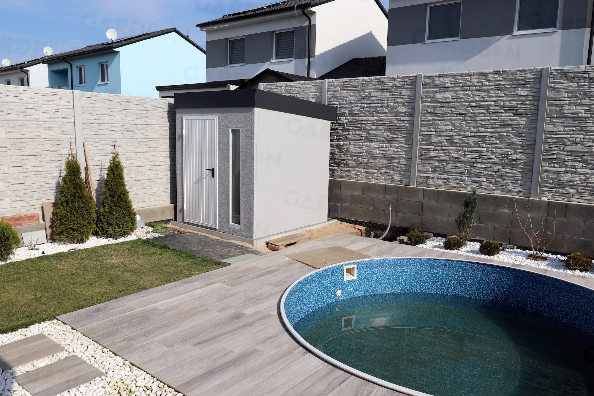 Záhradný domček v sivej omietke pri bazéne