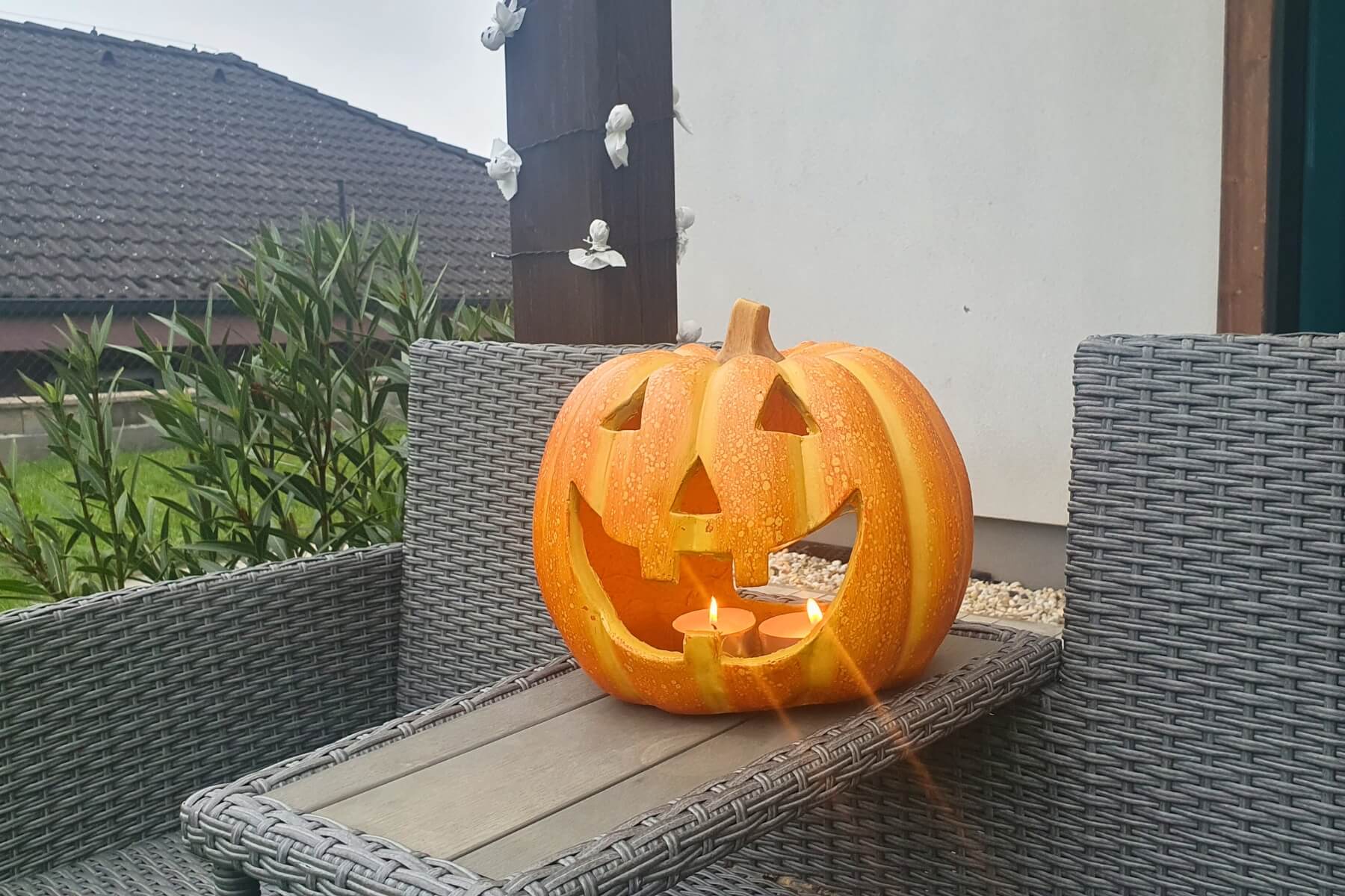 Umelá tekvica so sviečkou pod altánkom.