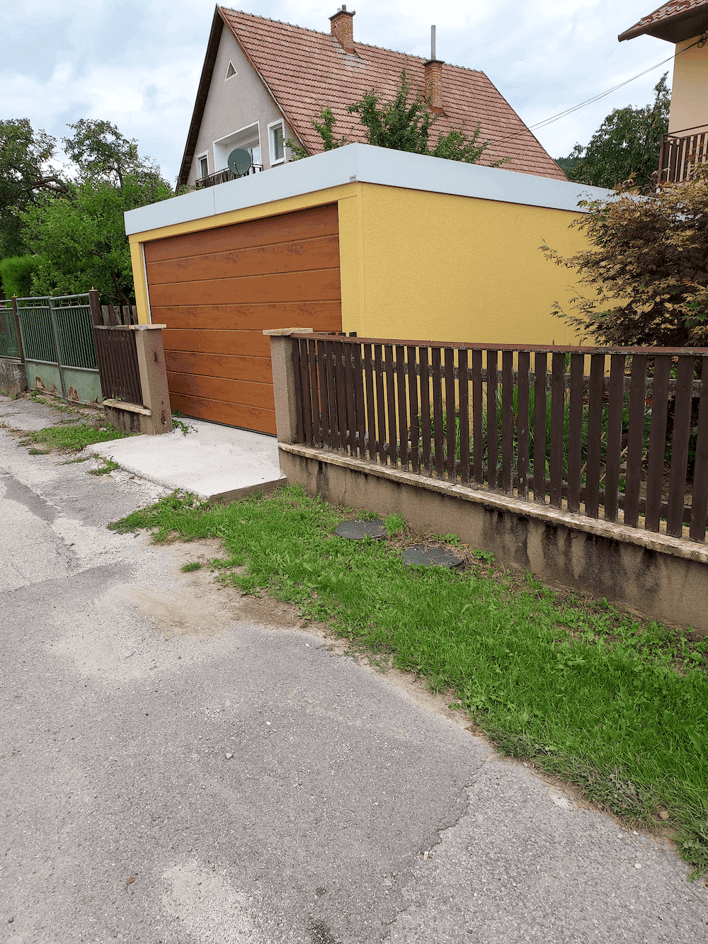 Garáž pre jedno auto v žltej omietke medzi plotom