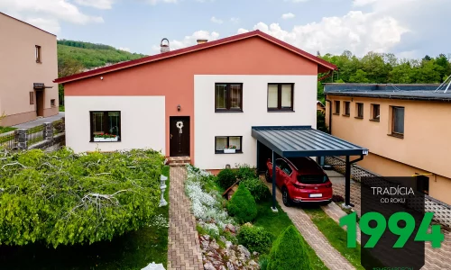 Červené auto pod prístreškom pri dome