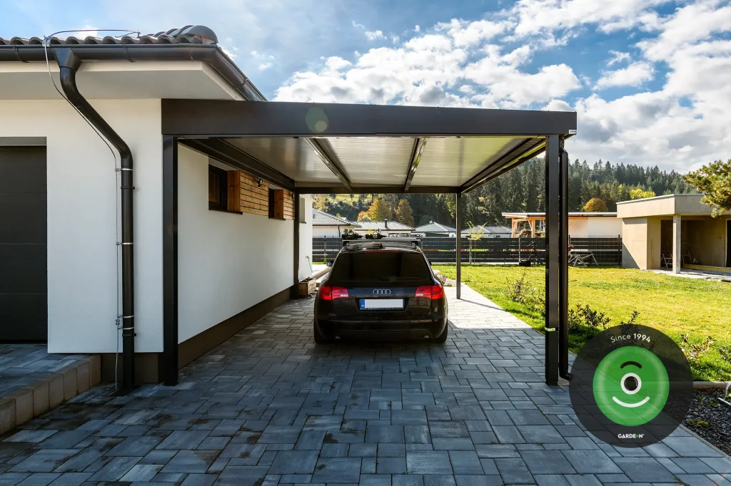 Jednoduch&yacute; pr&iacute;stre&scaron;ok pre auto s pultovou stechou vedľa rodinn&eacute;ho domu