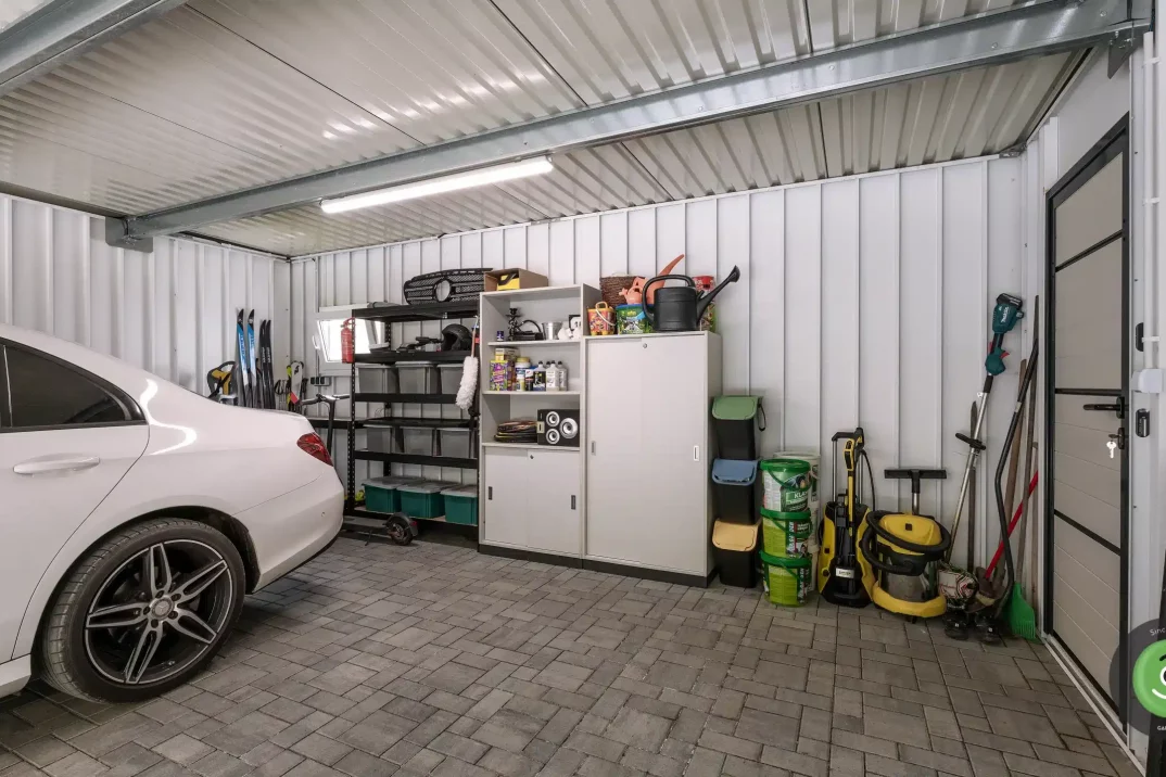 Interiér bielej garáže s montovanými regálmi a úložným priestorom.