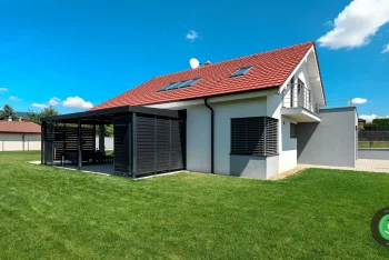 Čierna pergola dotýkajúca sa bieleho rodinného domu.