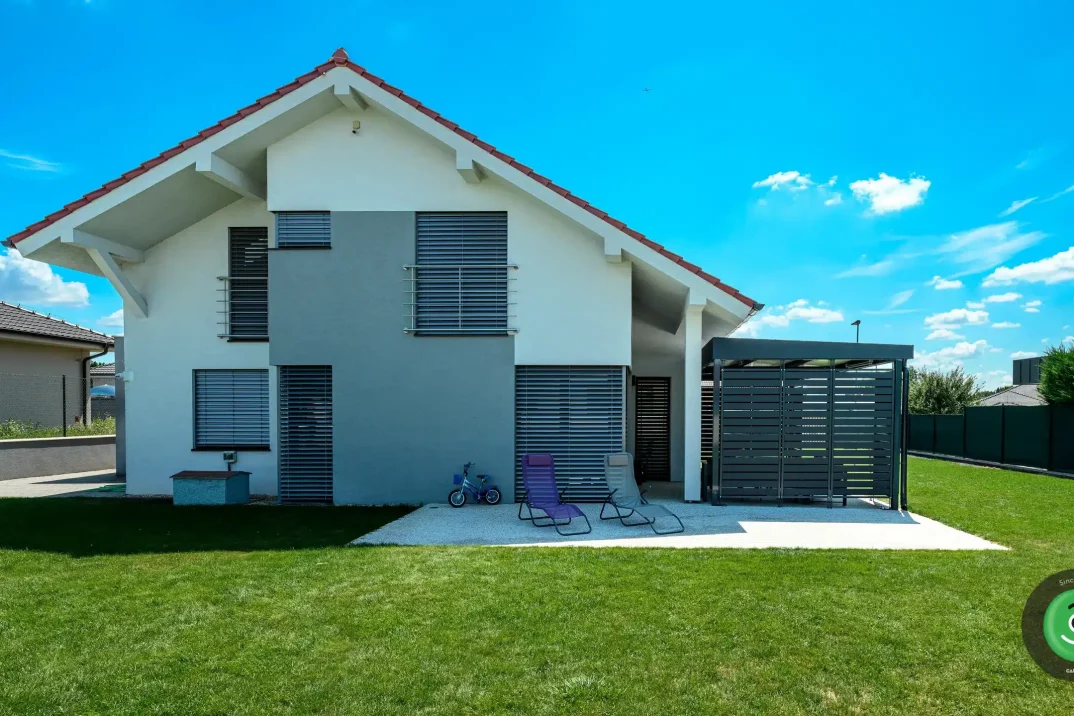 Bielo-sivý rodinný dom s montovanou čiernou pergolou.