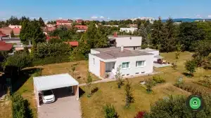 Pr&iacute;stre&scaron;ok pre dve aut&aacute; s bielou strechou vedľa bieleho domu.