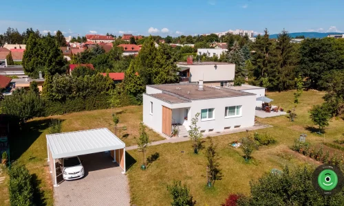 Prístrešok pre dve autá s bielou strechou vedľa bieleho domu.
