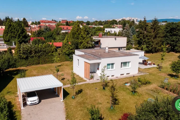 Prístrešok pre dve autá s bielou strechou vedľa bieleho domu.