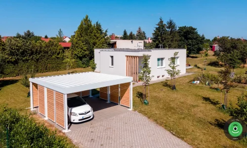 Prístrešok pre dve autá s bielou strechou medzi ovocnnými stromčekmi.