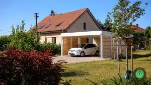 Pr&iacute;stre&scaron;ok pre dve aut&aacute; s bielou strechou medzi stromami v z&aacute;hrade.