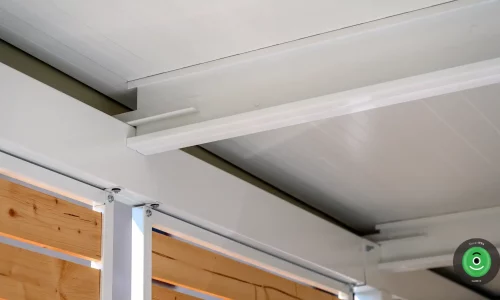 Detail bielych nosníkov pod izolovanou strechou na prístrešku