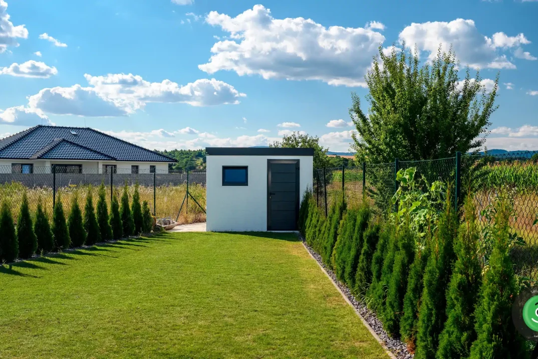 Záhradný domček s pultovou strechou na konci záhrady.