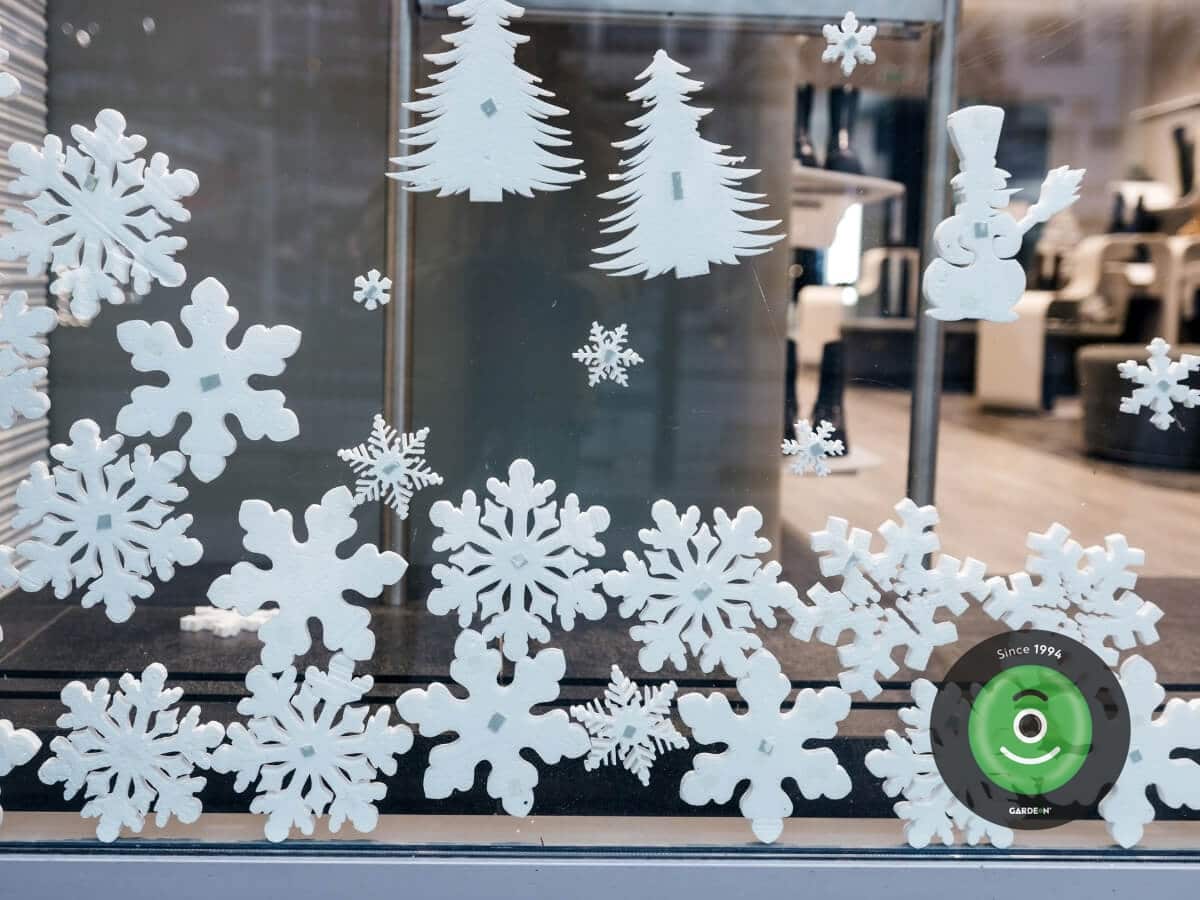 Biele vianočné nálepky na okná v tvare vločiek, stromčekov a snehuliaka.