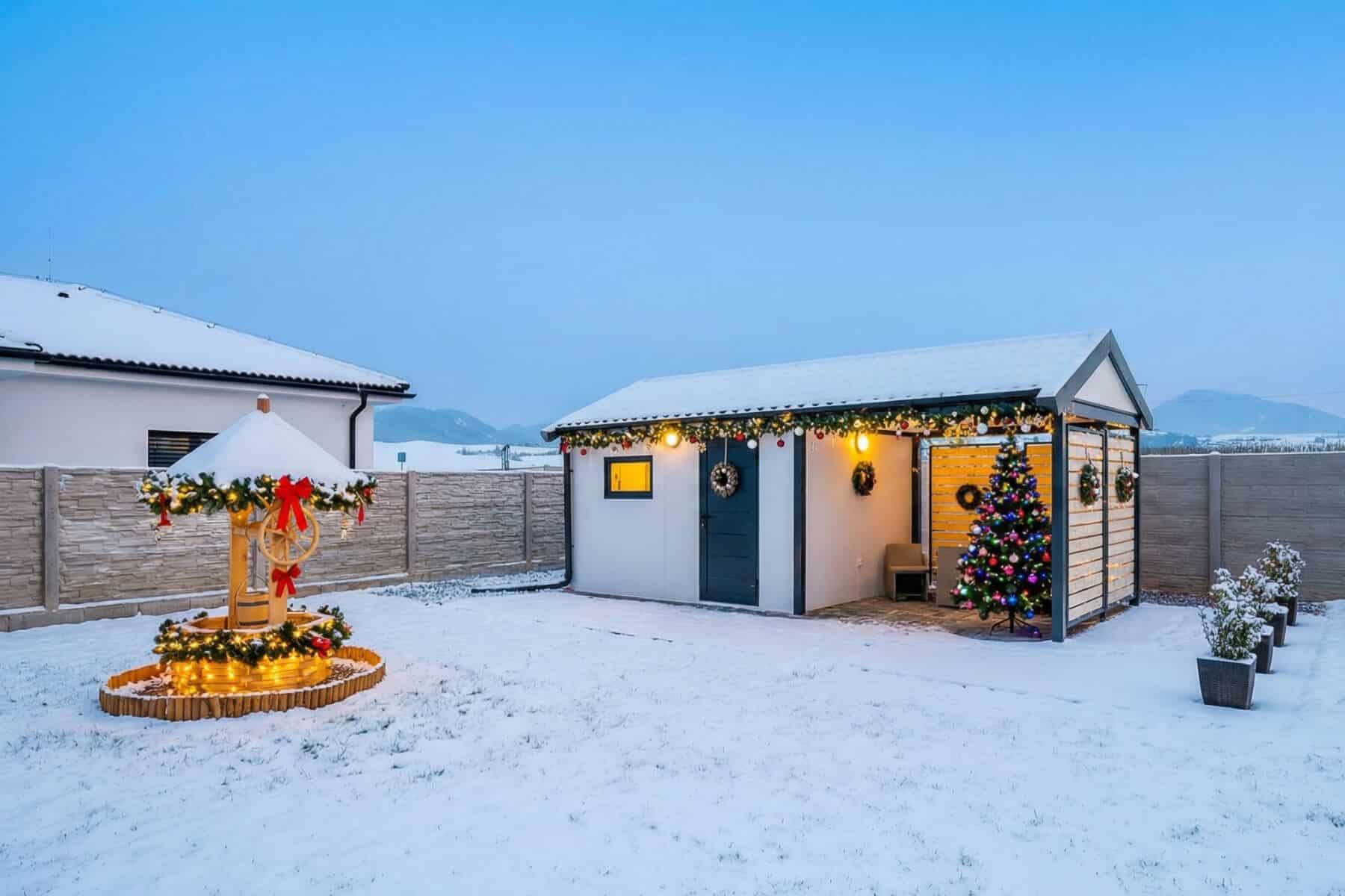 Vianočne vyzdobený záhradný domček s prístreškom.