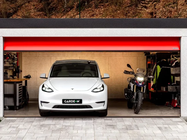 Tesla a motorka v garáži GARDEON s červenou bránou