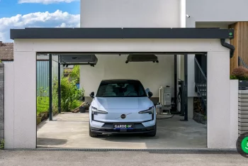 Auto zaparkované pod prístreškom s garážovou širokou bránou.