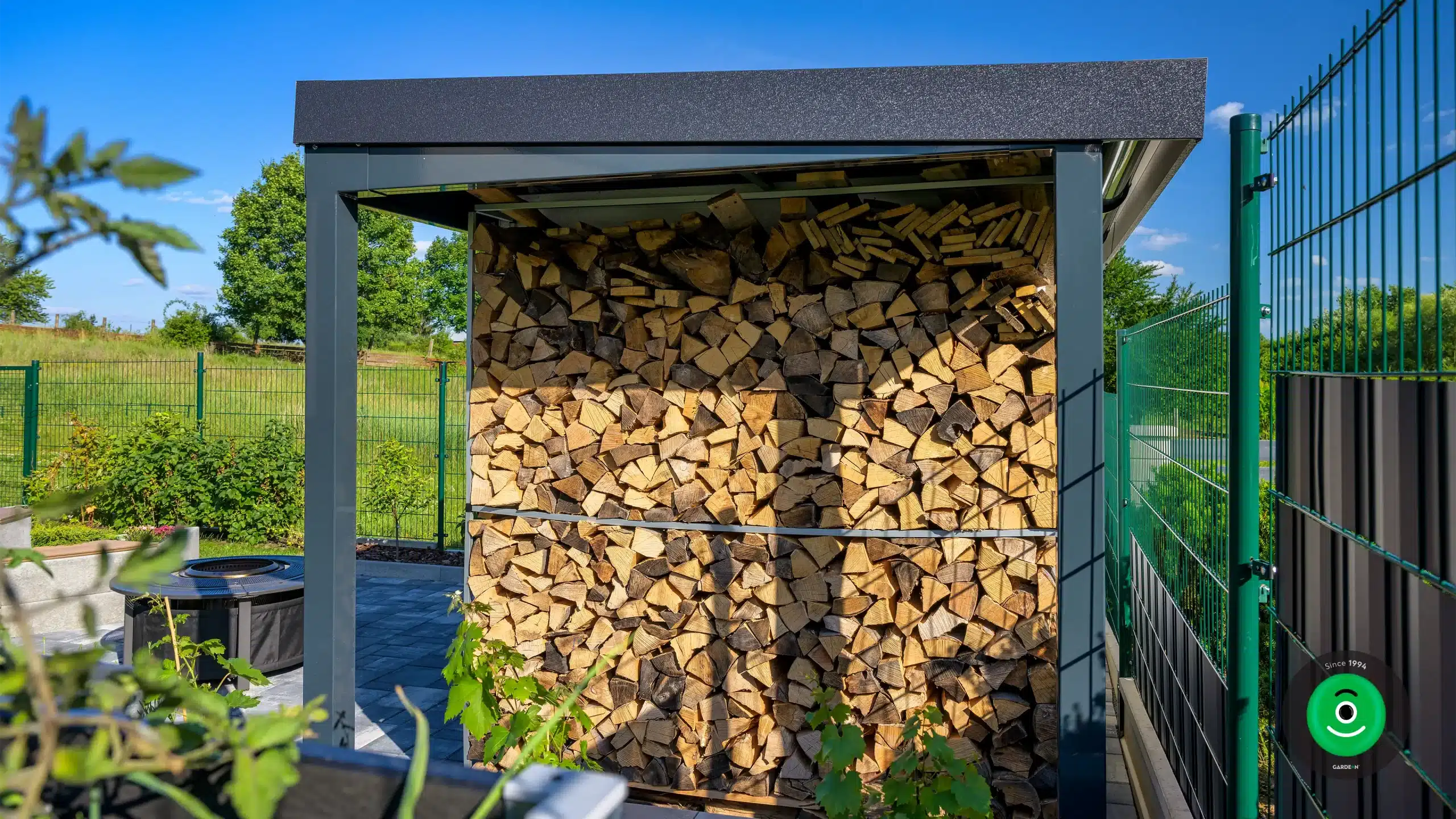 drevo uložené pod prístreškom vedľa záhradného domčeka