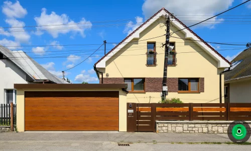 Montovaný prístrešok so žltou omietkou a širokou hnedou garážovou bránou