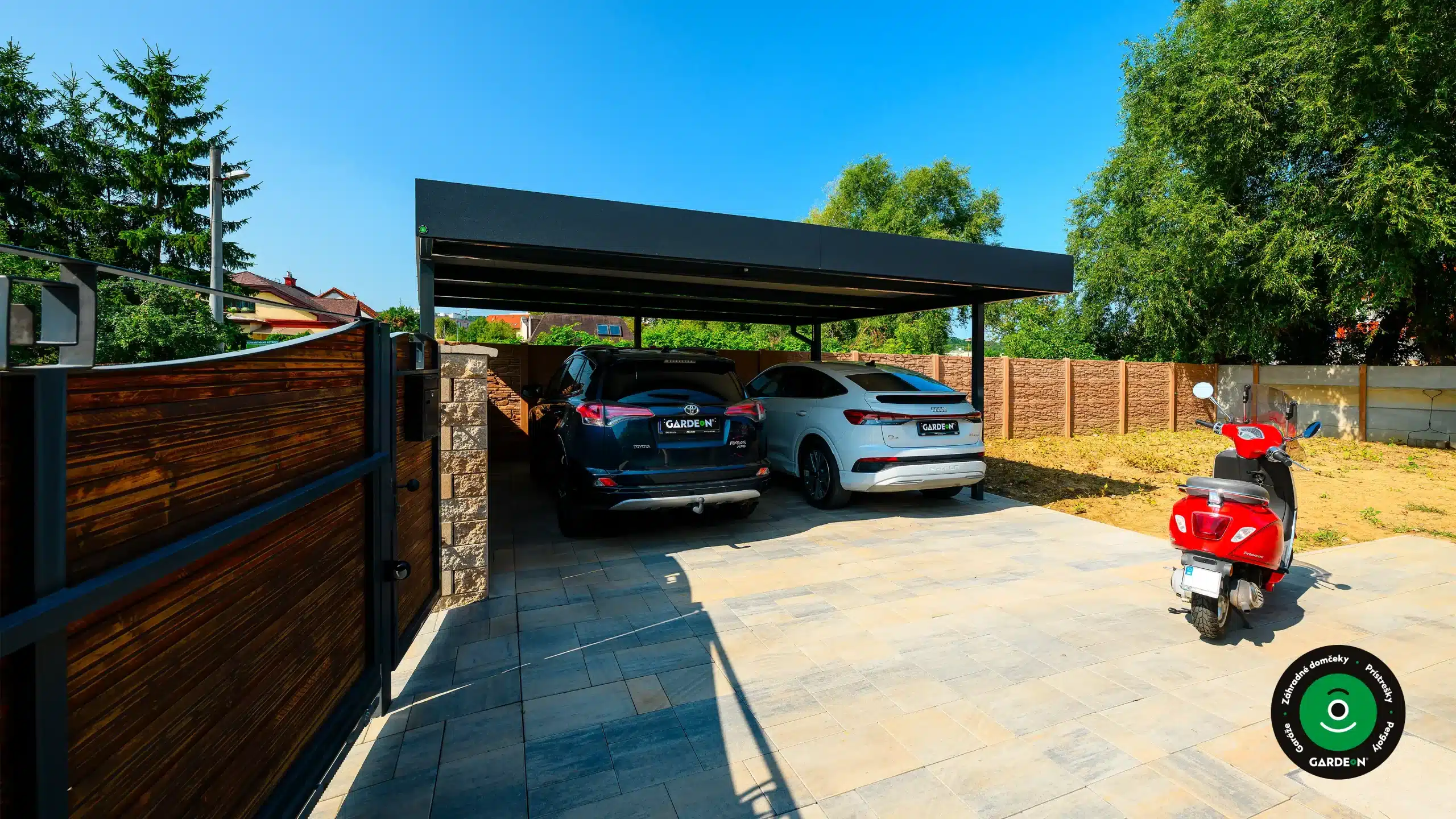 Moderný prístrešok pre dve autá s tmavou strechou a vydláždeným dvorom.