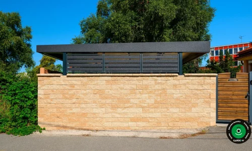 Pohľad zvonku na prístrešok ukrytý za kamenným múrom.