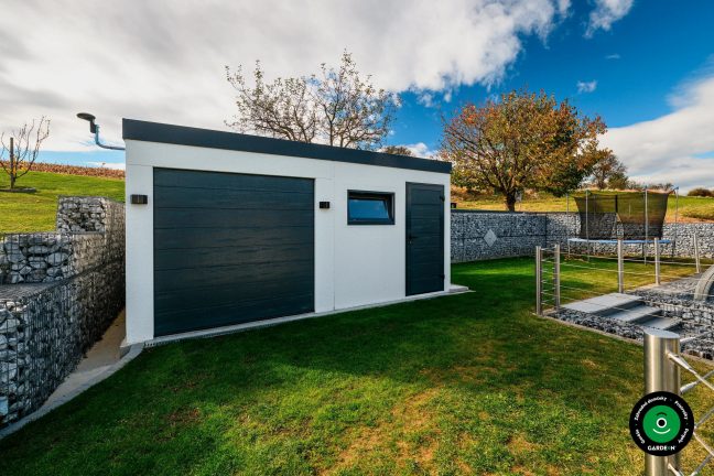 Garáž s pultovou strechou v upravenom zelenom a svahovitom prostredí