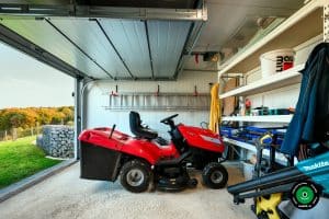 Detail gar&aacute;že s policami, n&aacute;rad&iacute;m a červenou z&aacute;hradnou kosačkou