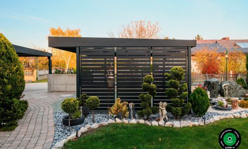 Bočná stena prístrešku pri okrasných drevinách a kamienkoch