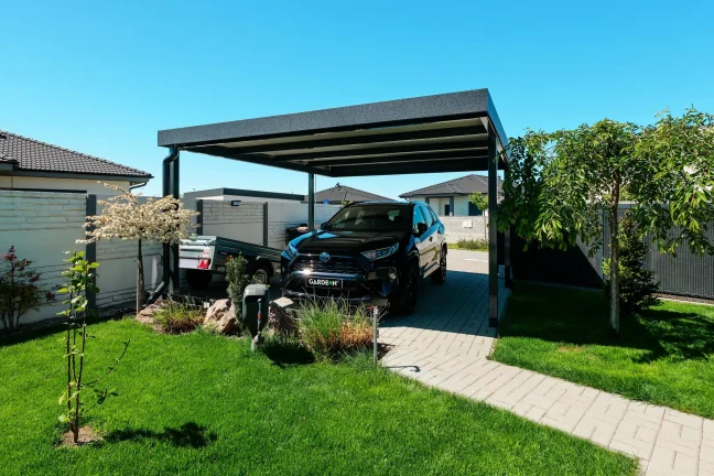 Priestranný prístrešok pre auto umiestnený pri upravenej modernej záhrade