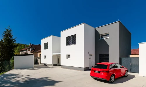 Moderný záhradný domček s prístreškom pri minimalistickom rodinnom dome