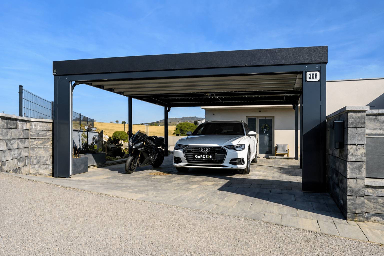 Antracitov&yacute; pr&iacute;stre&scaron;ok Gardeon s motorkou a autom pri rodinnom dome.