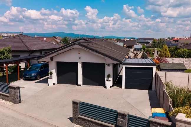 Garáž pre jedno auto s antracitovou pultovou strechou a tmavou sekčnou bránou, pohľad spredu