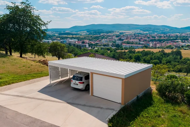 Kombinovaná stavba garáže a prístrešku s tehlovou omietkou a bielou strechou.