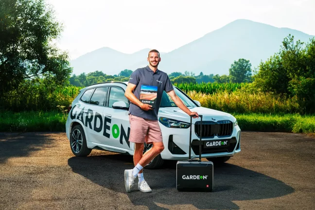 Zamestnanec GARDEON so vzorkovníkom a kufríkom pred firemným BMW v prírode.