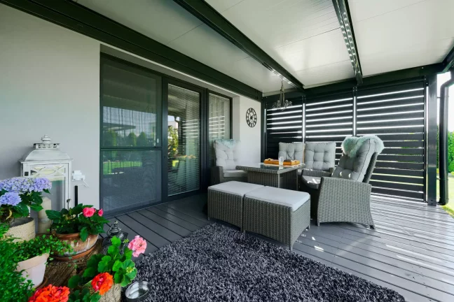 Antracitová pergola s kovovými lamelami a ratanovým sedením na terase.