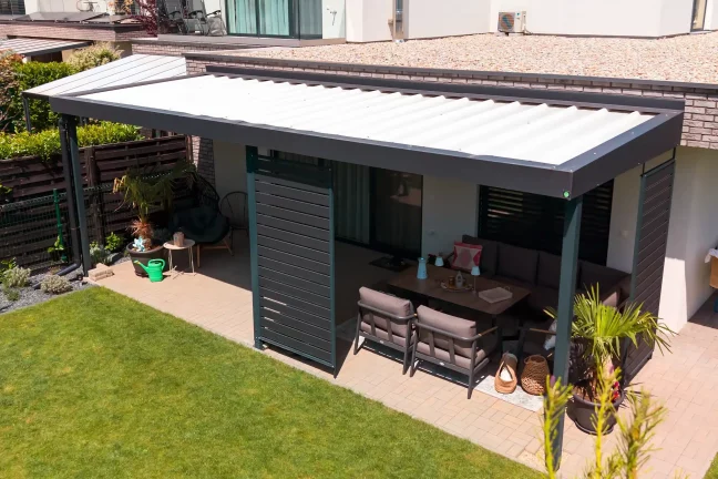 Pergola so záhradným sedením pri tmavej fasáde, dláždená terasa