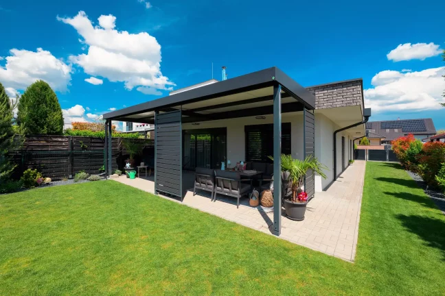 Antracitová pergola so záhradným sedením, pohľad zboku na zelenú záhradu