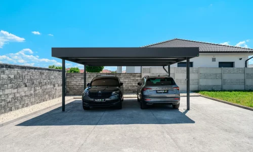 Antracitový dvojgarážový prístrešok s plochou strechou pri rodinnom dome kryje dve SUV.