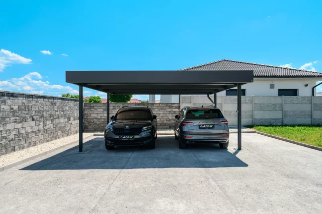 Antracitový dvojgarážový prístrešok s plochou strechou pri rodinnom dome kryje dve SUV.