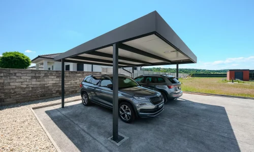 Plochá antracitová strecha prístrešku chráni dve SUV pri rodinnom dome.