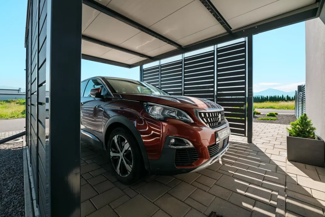 Prístrešok s antracitovou kovovou výplňou s parkujúcim SUV.