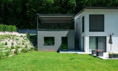 Antracitová pergola s pultovou strechou osadená na vyvýšenom podklade.