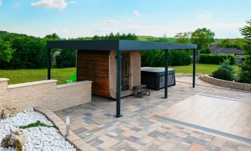 Antracitová pergola pri bazéne s priehľadným krytom, biely štrk a dláždená plocha okolo
