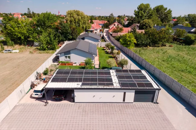 Letecký pohľad na garáž s prístreškom a susednými domami s vežou kostola