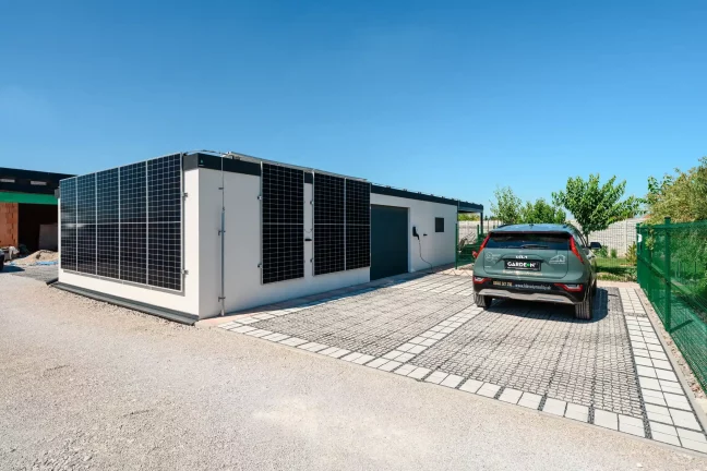 Pohľad na dom so solárnou stenou zeleným autom a bránou