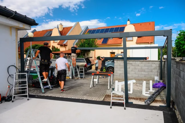Montážnici stavajú oceľovú konštrukciu prístrešku na ulici