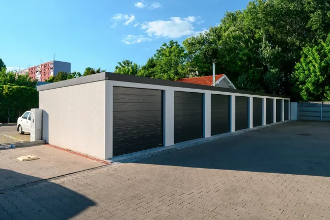 Rad tmavých garáží v rannom svetle s bielym autom