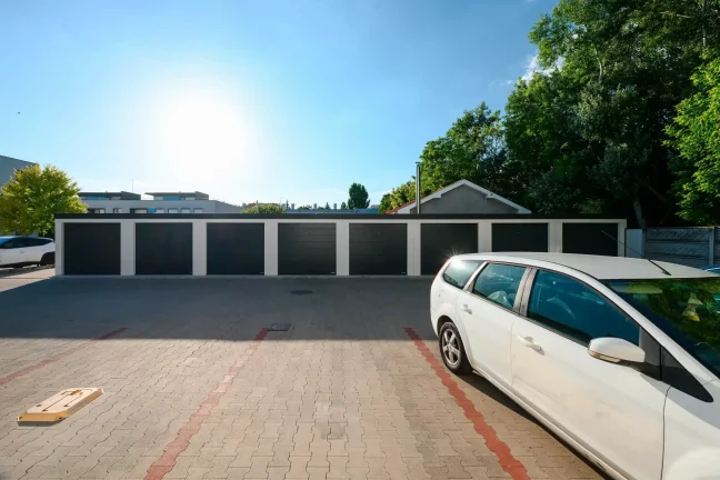 Pohľad na rad garáží pri plote a bytovom dome
