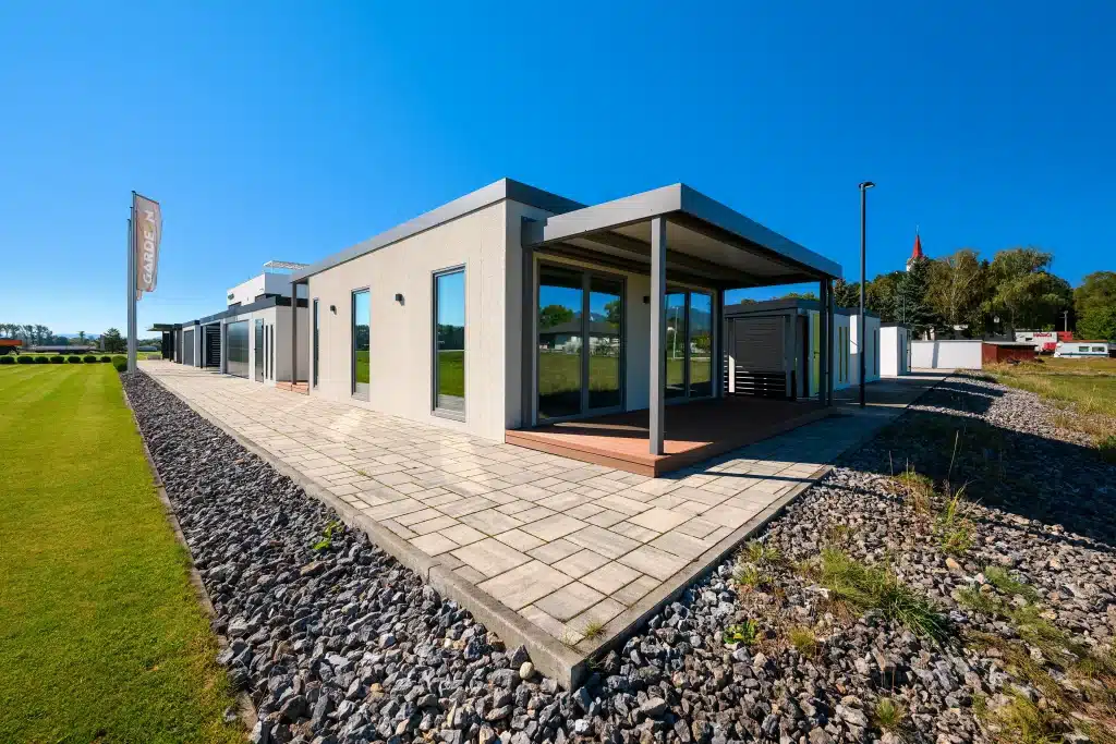 Tiny house s krytou terasou a dláždeným chodníkom pozdĺž trávnika