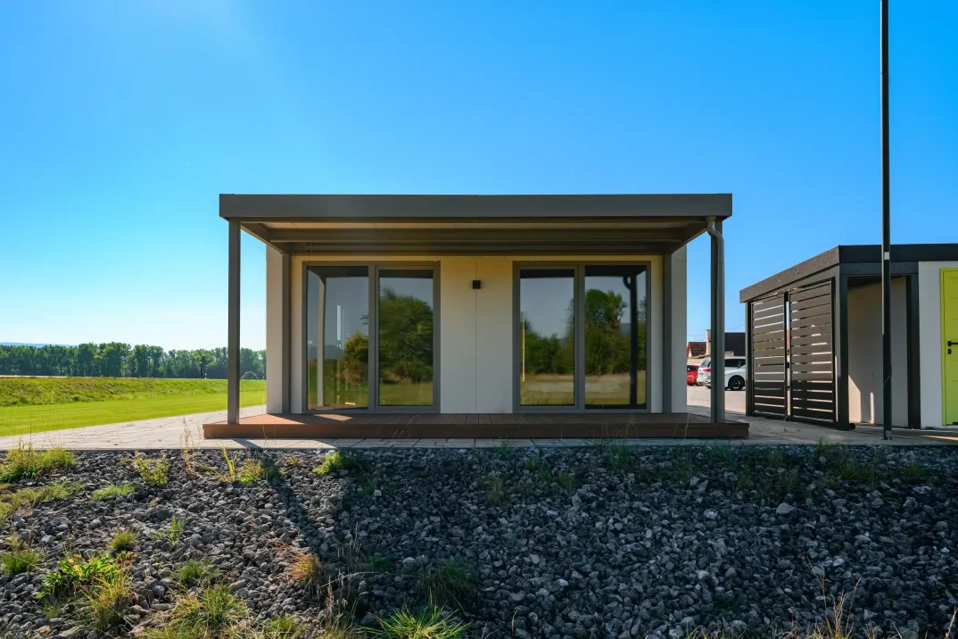 Tiny house spredu s krytou drevenou terasou a posuvnými presklenými dverami